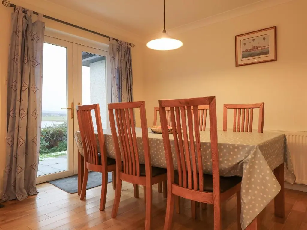 a dining room with a table and chairs and a window at Glaven in Bonar Bridge