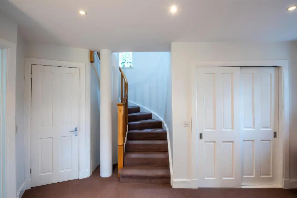 a hallway with white walls and stairs with white doors at Kerrisdale in Dornoch