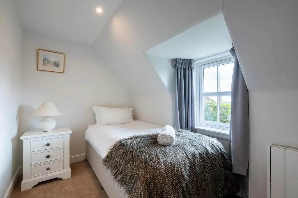 a small bedroom with a bed and a window at Kerrisdale in Dornoch