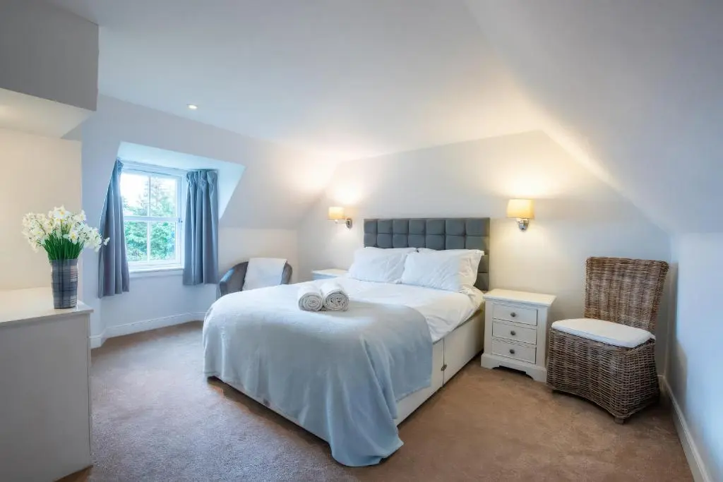 a bedroom with a white bed and a chair at Kerrisdale in Dornoch