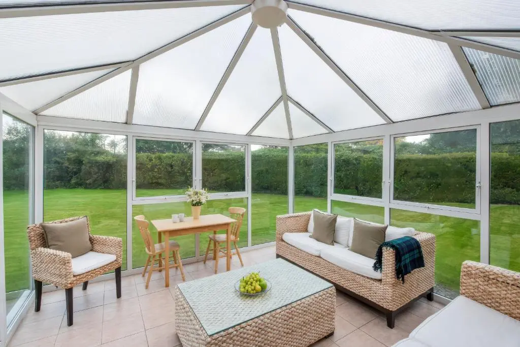 a conservatory with a glass roof with a table and chairs at Kerrisdale in Dornoch