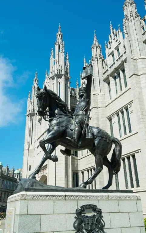 a statue of a man riding a horse in front of a building at Buttermere Cottage in Banff