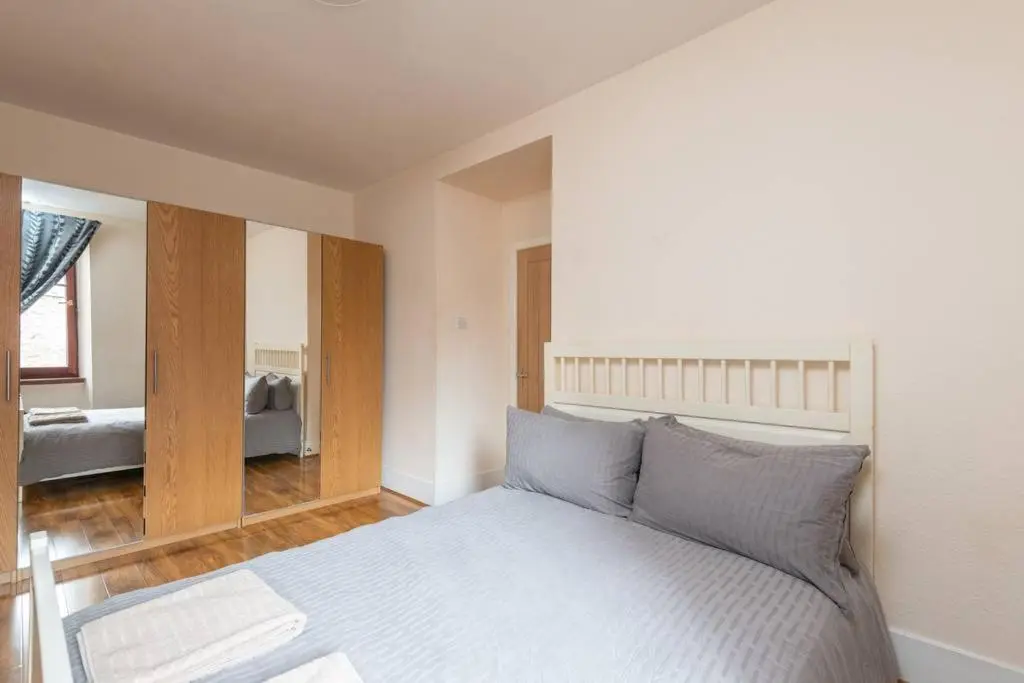 a bedroom with a large white bed with blue pillows at Ness Central Apartment - Greig Street in Inverness