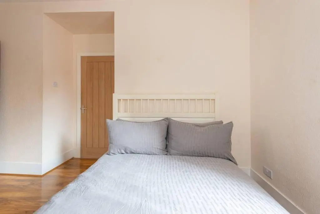 a bed with blue pillows in a white room at Ness Central Apartment - Greig Street in Inverness