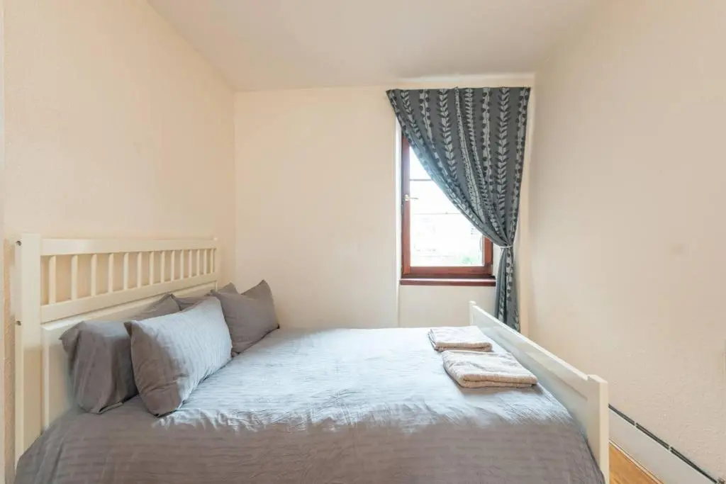a small bedroom with a bed with a window at Ness Central Apartment - Greig Street in Inverness