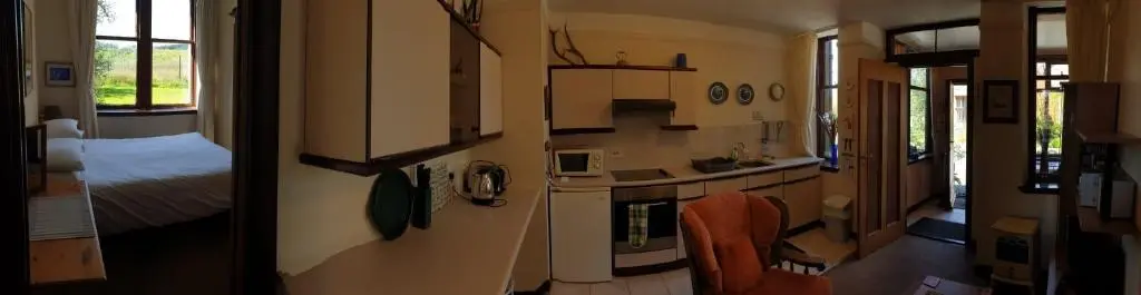 a small room with a kitchen and a bed at Meadowside Cottages in Balavil