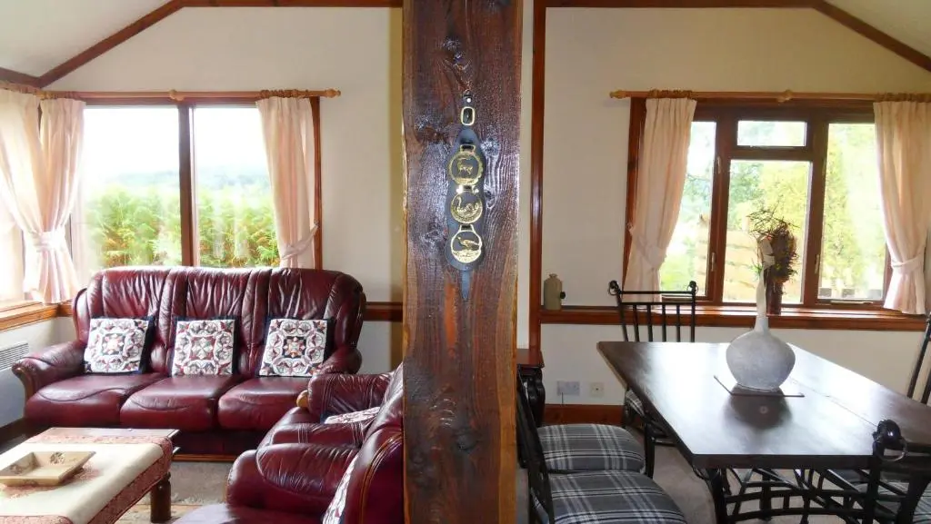a living room with a couch and a table at Meadowside Cottages in Balavil