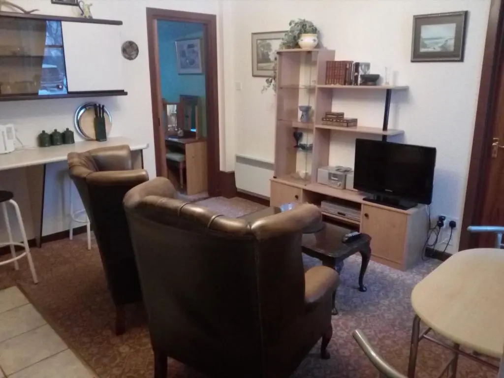 a living room with two chairs and a television at Meadowside Cottages in Balavil