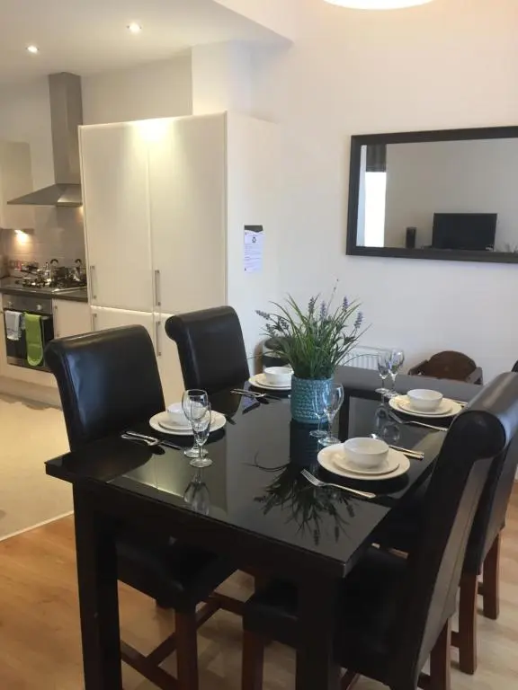 a dining room table with black chairs and a black table with wine glasses at Inverness City Suites in Inverness