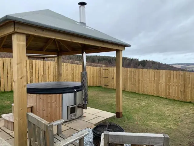 a wooden gazebo with a grill in a yard at Hillside Havens in Dufftown