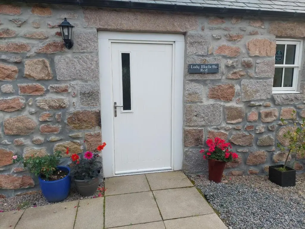 a white door of a stone building with potted plants at Lady Macbeths Rest in Banchory