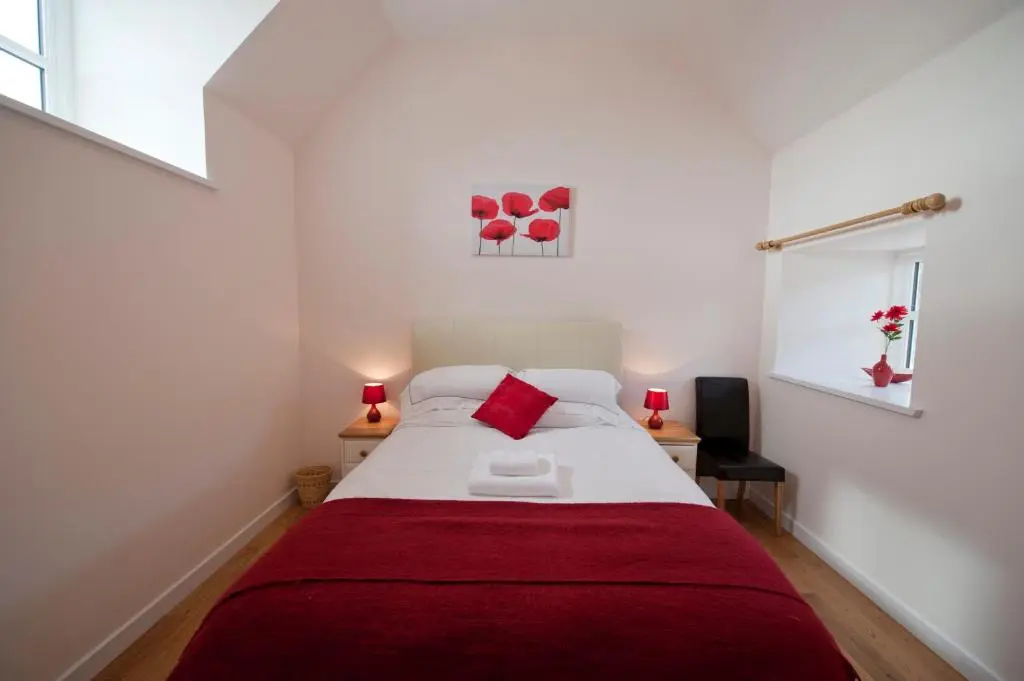a bedroom with a large bed with a red blanket at Lady Macbeths Rest in Banchory