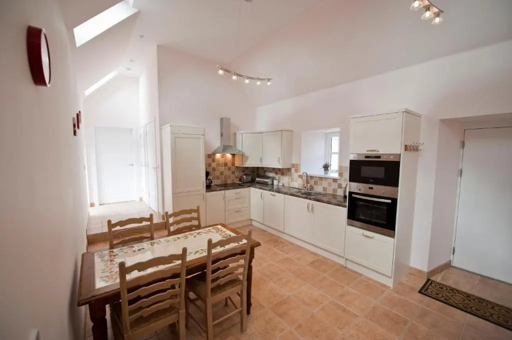 a kitchen with white cabinets and a table and chairs at Lady Macbeths Rest in Banchory