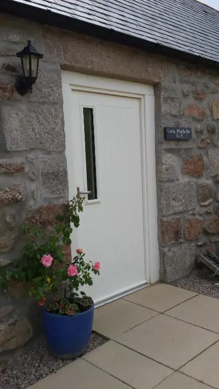 a white garage door on a stone building with a plant at Lady Macbeths Rest in Banchory