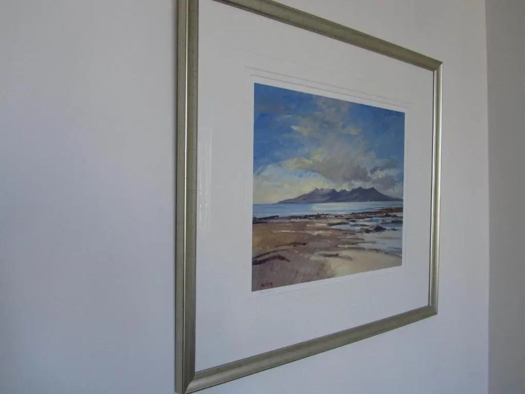 a framed painting of a beach with a mountain at Bridge Street Apartments in Inverness