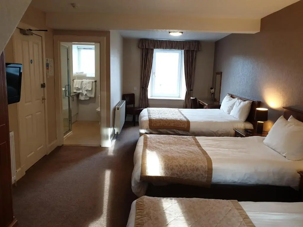 a hotel room with two beds and a television at Commercial Hotel in Alness