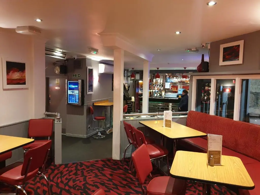 a restaurant with tables and chairs and a bar at Commercial Hotel in Alness