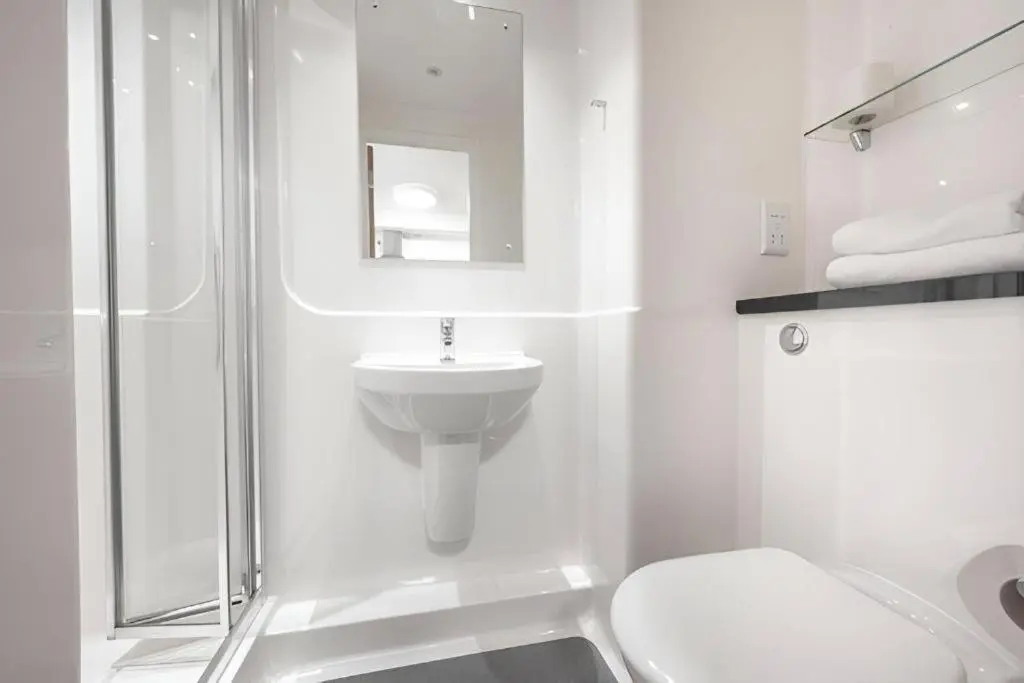 a white bathroom with a toilet and a sink at UHI Dornoch- Campus Accommodation in Dornoch
