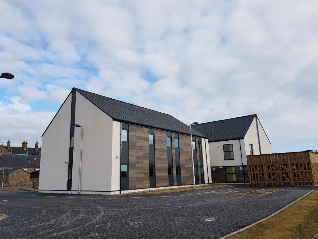 a large white building with a black roof at UHI Dornoch- Campus Accommodation in Dornoch