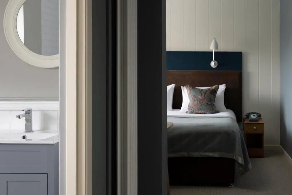 a bedroom with a bed with a blue headboard and a sink at Balmoral Arms in Ballater
