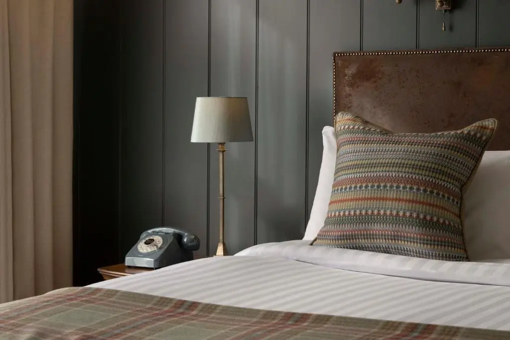 a bedroom with a bed with a lamp and a clock at Balmoral Arms in Ballater