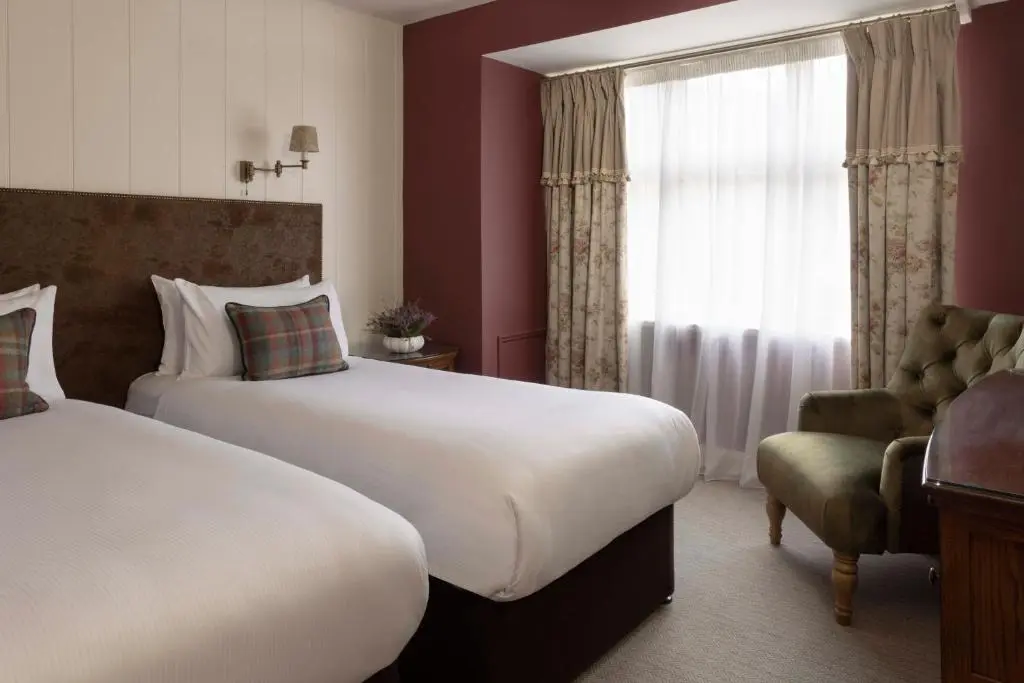a hotel room with two beds and a window at Balmoral Arms in Ballater