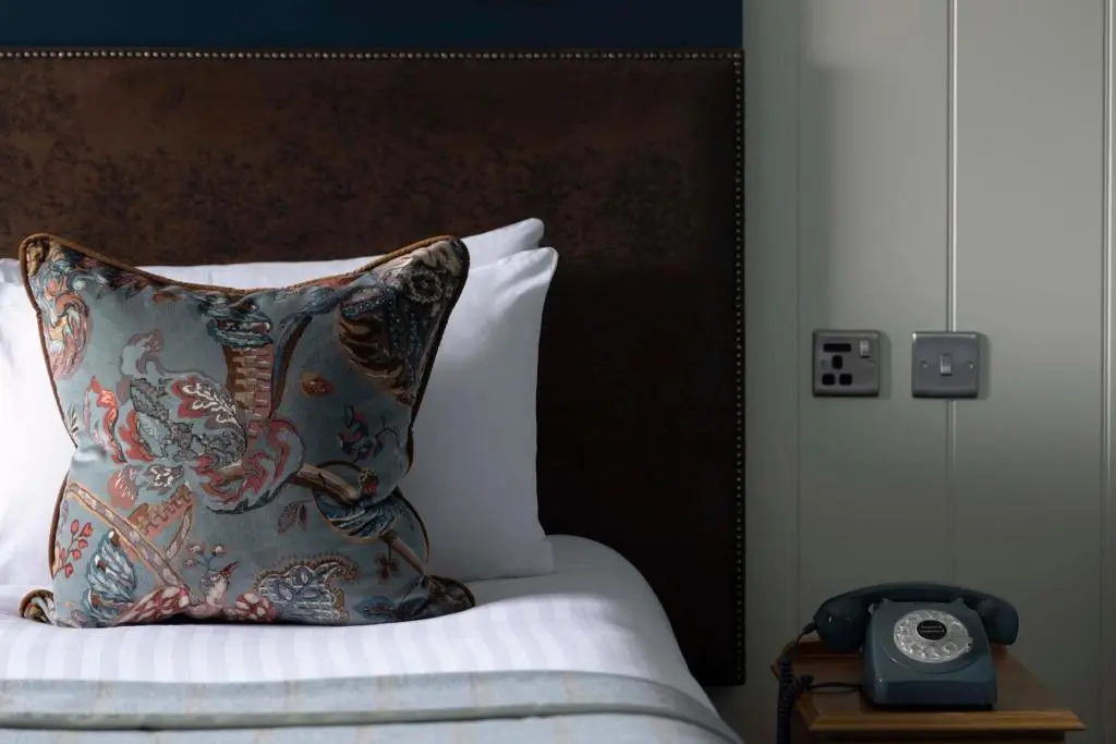 a bed with a pillow and a clock on a night stand at Balmoral Arms in Ballater
