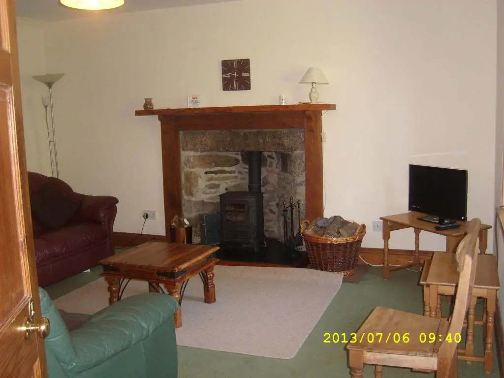 a living room with a fireplace and a tv at Parkmore Holiday Cottages in Dufftown