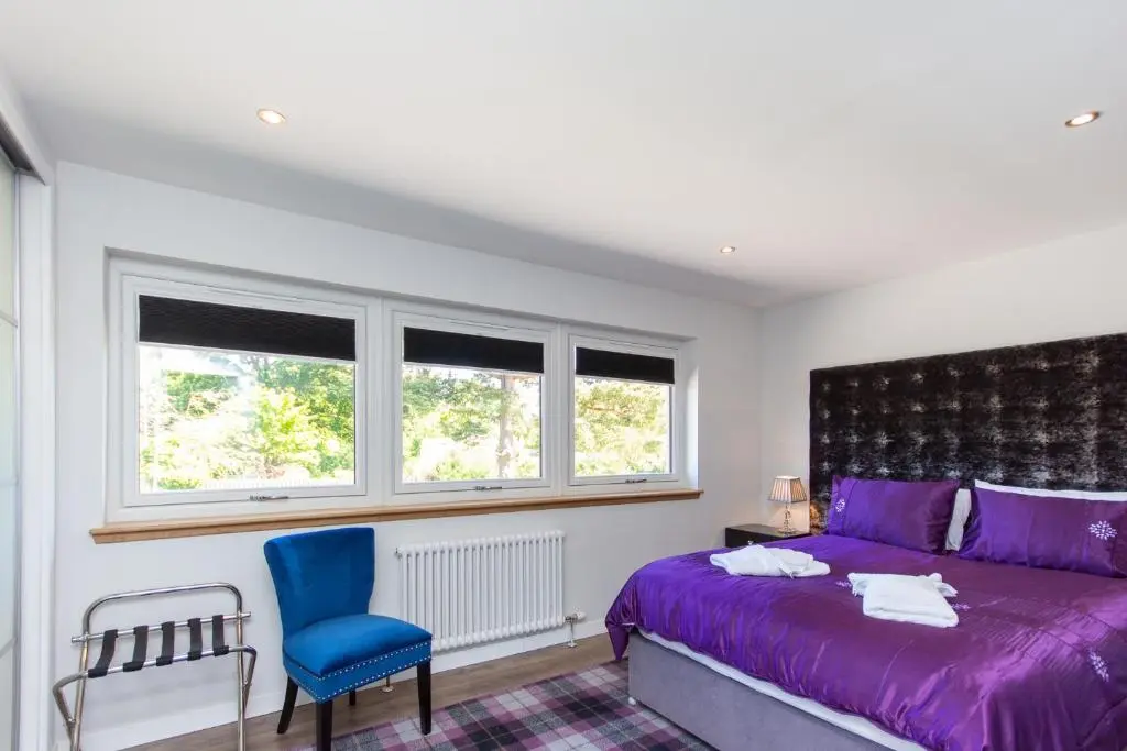 a bedroom with a purple bed and a blue chair at Loch Earn in Inverness