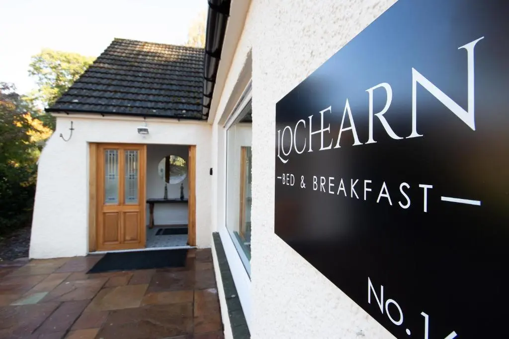 a sign for the front door of a house at Loch Earn in Inverness