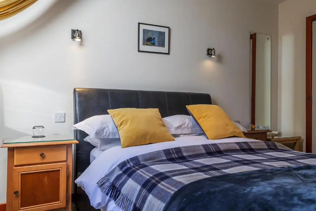 a bedroom with a bed with yellow pillows on it at Crubenbeg Country House in Newtonmore