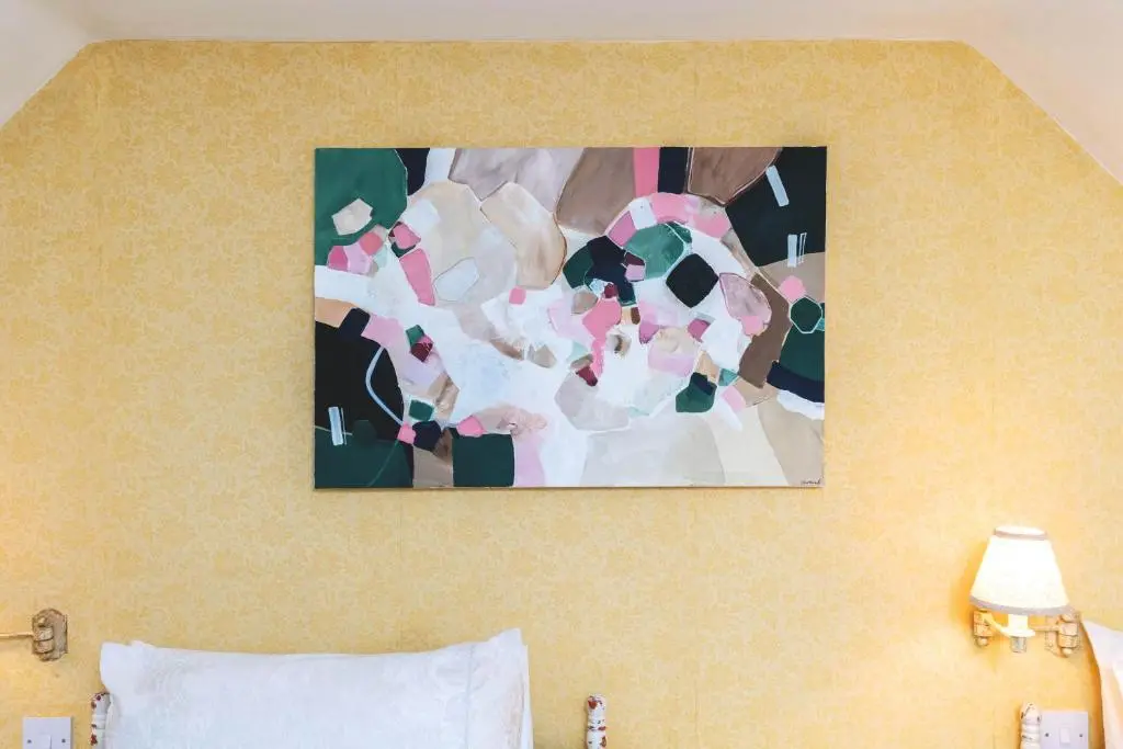a painting hanging on a wall above a bed at Riverside Cottage with wood fired hot tub in Cairngorms in Ballater