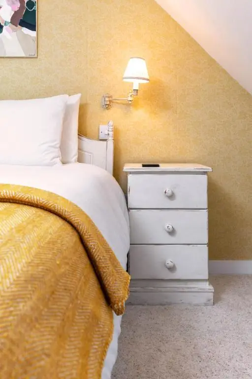 a bedroom with a bed and a night stand with a lamp at Riverside Cottage with wood fired hot tub in Cairngorms in Ballater