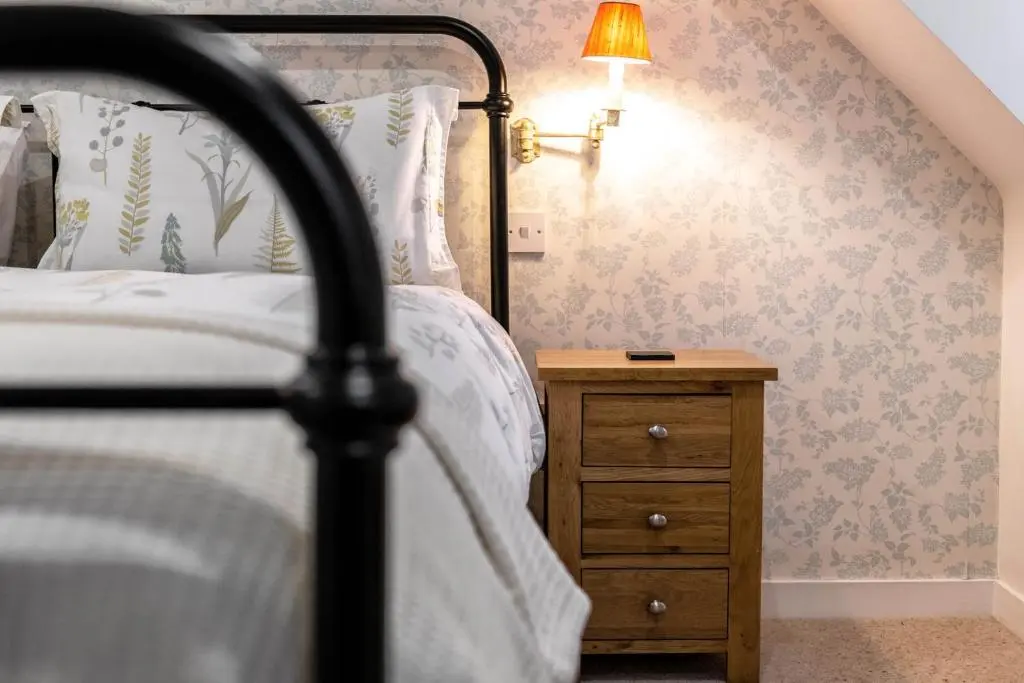 a bedroom with a bed and a night stand with a lamp at Riverside Cottage with wood fired hot tub in Cairngorms in Ballater