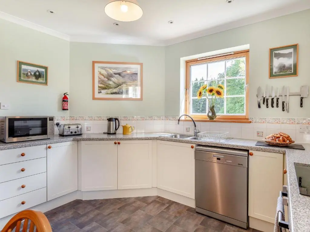a kitchen with white cabinets and a window at The Old Laundry in Grantown on Spey