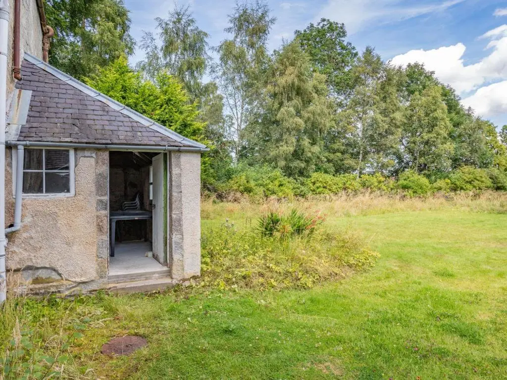 an old brick house in a field of grass at The Old Laundry in Grantown on Spey