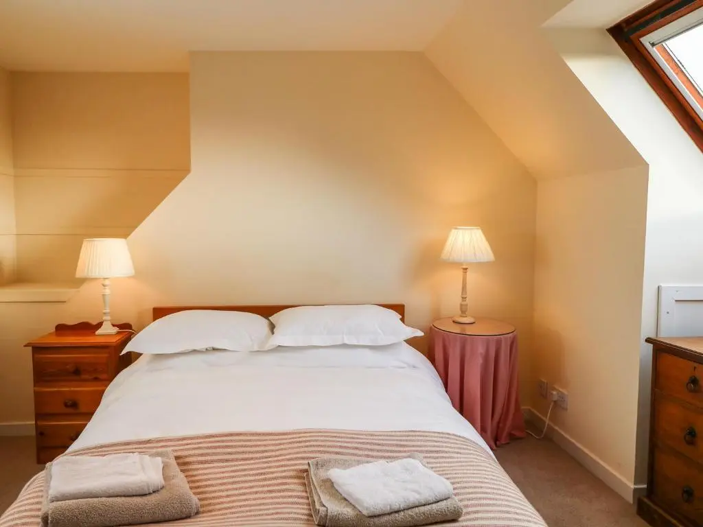 a bedroom with a large bed with two lamps at Newlands in Archiestown