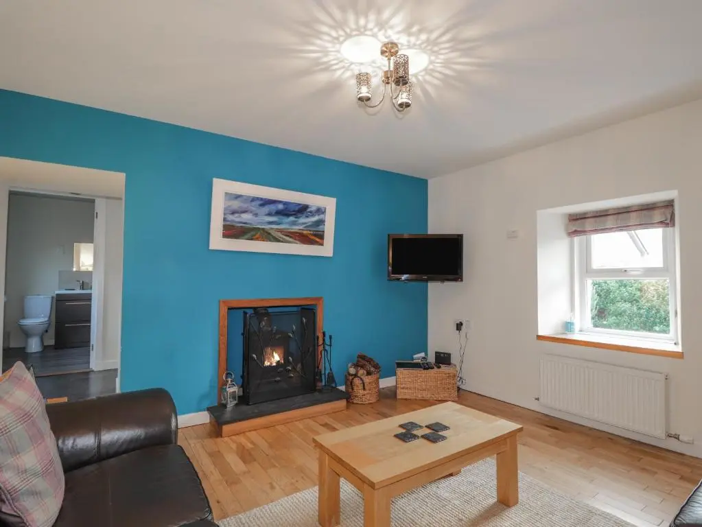 a living room with blue walls and a fire place at Lilac Cottage in Strathpeffer