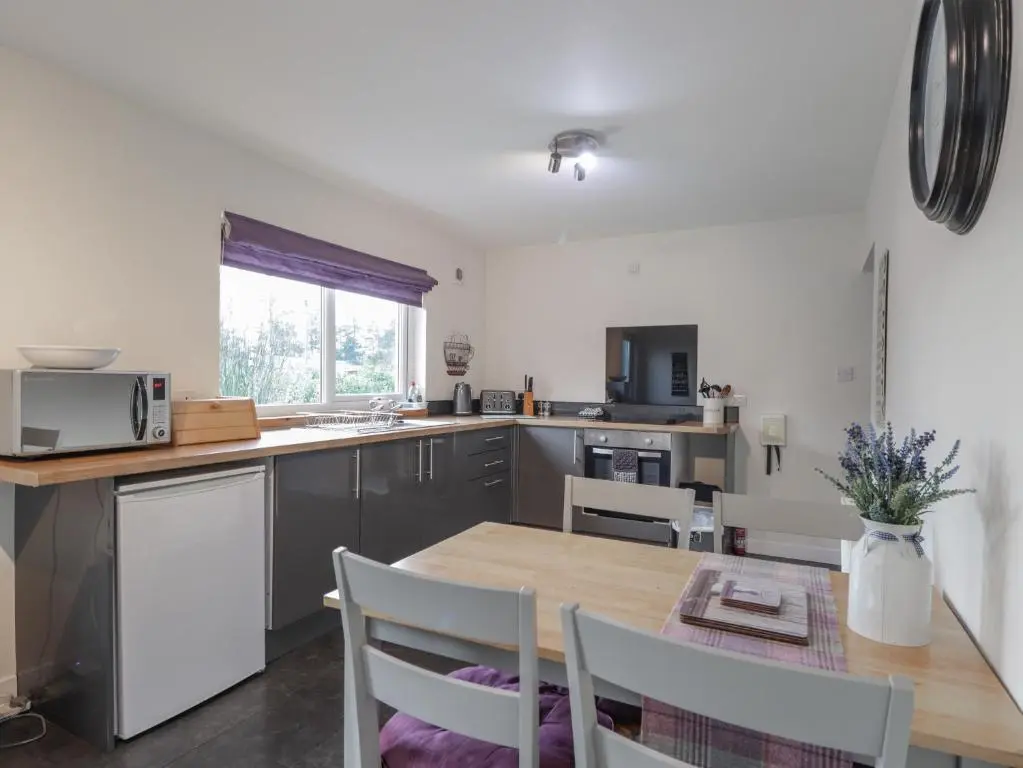 a kitchen with a wooden table and a dining room at Lilac Cottage in Strathpeffer