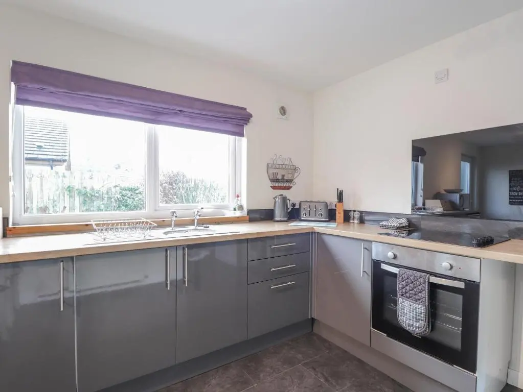 a kitchen with stainless steel appliances and a window at Lilac Cottage in Strathpeffer