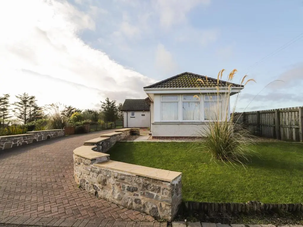 a house with a brick walkway in front of a yard at Rose Cottage in Lybster