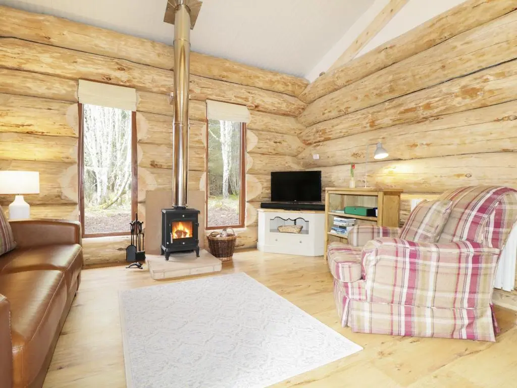 a living room with a couch and a stove at Heron Lodge in Inverness