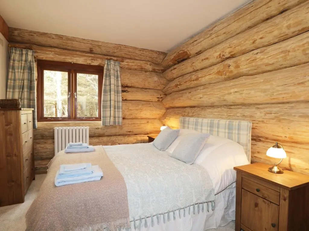 a bedroom with a bed and a wooden wall at Heron Lodge in Inverness