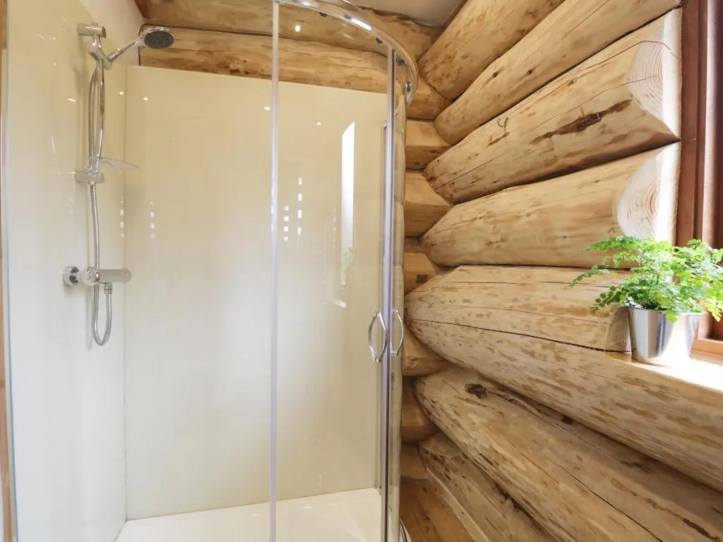 a bathroom with a shower and a stone wall at Heron Lodge in Inverness
