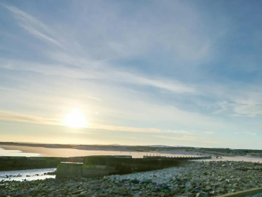 a beach with the sun setting over the water at Seascape in Lossiemouth