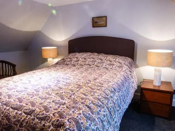 a bedroom with a bed with two lamps and two tables at Grace Cottage in Buckie
