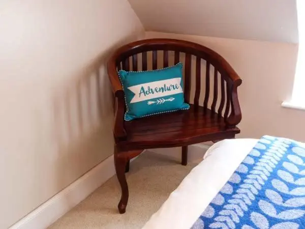 a wooden chair with a blue pillow sitting next to a bed at Grace Cottage in Buckie