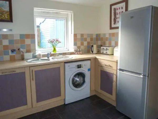 a kitchen with a refrigerator and a washing machine at Grace Cottage in Buckie