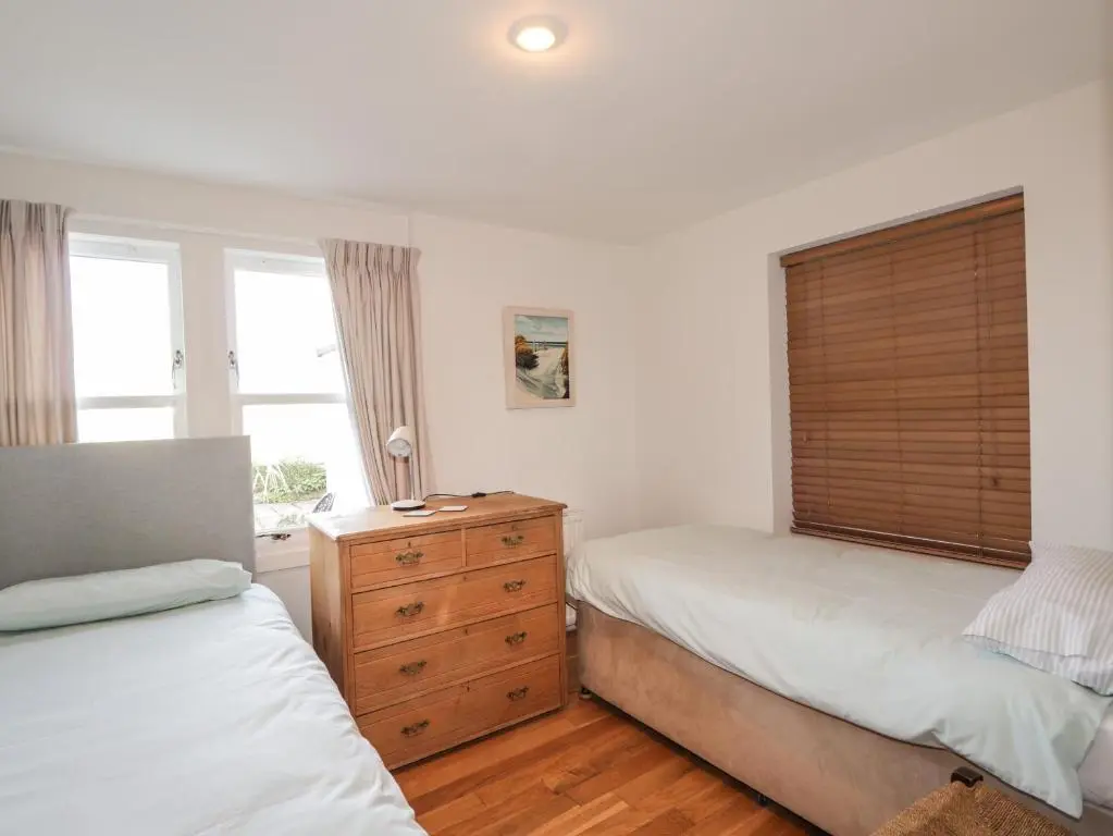 a bedroom with two beds and a dresser and a window at Seaview in Nairn