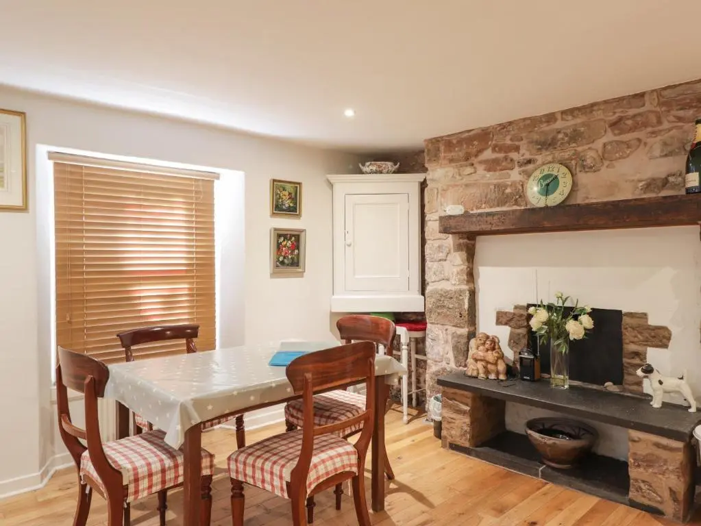 a dining room with a table and chairs and a fireplace at Seaview in Nairn